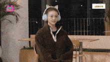 a woman wearing a cat ear ear warmer and headphones looks at the camera