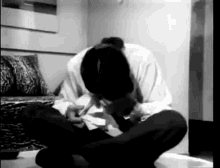 a man is sitting on the floor in a living room with his head down .