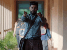 a man with a beard and a messenger bag pointing at the camera