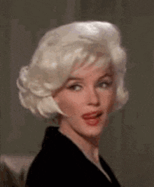 a woman with blonde hair is wearing a black jacket and making a funny face .