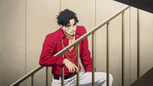 a man in a red shirt sits on a railing
