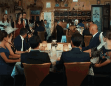 a group of people sitting at a table in front of a kocak hotel sign