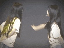 two girls with long black hair are dancing together