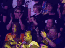 a group of people are sitting in a dark room and one of them is wearing a shirt that says " can i "