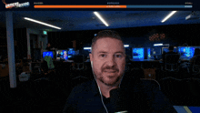 a man sitting in front of a microphone with the words gamersgiving on the screen behind him