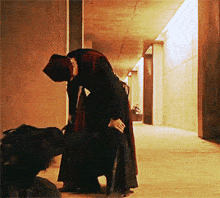 a woman in a long black dress is kneeling down