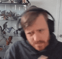 a man with a beard wearing headphones is sitting in front of a glass display case .