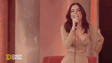 a woman singing into a microphone with comedy central written on the bottom