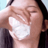 a woman is drinking a glass of water from a square glass