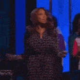 a woman in a leopard print dress is standing on a stage in front of a blue wall .