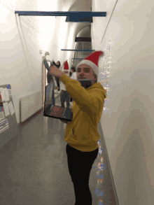 a man wearing a santa hat is holding a laptop over his head