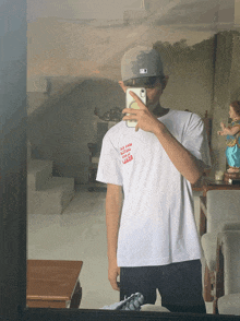 a man taking a picture of himself in a mirror while wearing a white shirt that says " all good all bad all bad "