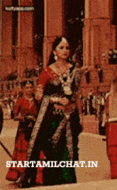 a woman in a green saree is standing in front of a crowd and the website starttamilchat.in is displayed on the bottom