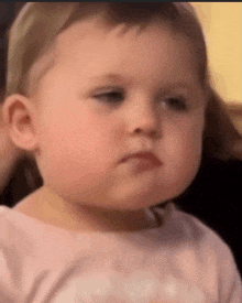 a baby girl is making a funny face while looking at the camera .