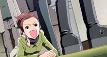 a girl in a green jacket is sitting at a table with her mouth open and making a funny face .