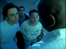 a group of men are standing around a man in a straight jacket