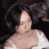 a woman wearing headphones and a white shirt is sitting in front of a computer screen .
