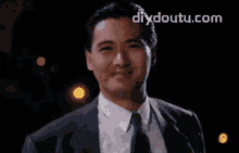a man in a suit and tie is smiling and the website diydoutu.com is visible behind him