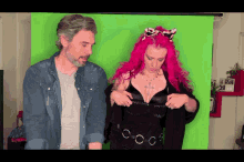 a man and a woman with pink hair are standing in front of a green background