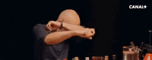 a man in a floral jacket is dancing with his arms outstretched in front of a glass of wine .