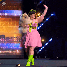 a woman in a pink dress is holding a dog