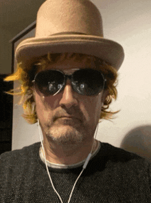 a man wearing a hat and sunglasses has ear buds in his ears
