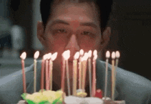 a man blowing out candles on a birthday cake .