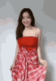 a woman is wearing a red top and a plaid skirt and smiling .