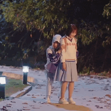 two girls are walking down a sidewalk and one has a shirt that says h-o-ah