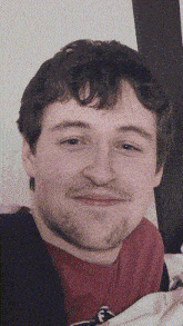 a man with a beard wearing a red shirt with the letter f on the front