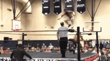a wrestler is jumping in the air in a wrestling ring .
