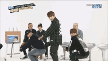 a group of young men are dancing in front of a sign that says mbc everyo