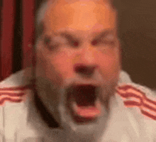 a man with a beard is making a funny face with his mouth wide open .