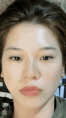 a close up of a woman 's face with a checkered shirt in the background
