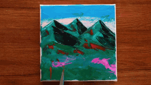 a small painting on a wooden table shows mountains