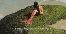 a woman with a red tail is sitting on a rock with the words compre mi primer a cola de sirena below her