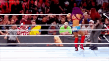 a woman is standing in a wrestling ring with a referee and a crowd watching .