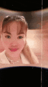 a woman with a ponytail and a necklace is smiling .