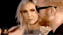 a man with a beard and sunglasses looks at a woman with blonde hair