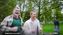 two men are running in a park with a nbc logo in the corner