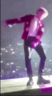 a man in a purple jacket is dancing on a stage in front of a crowd