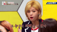 a woman with blonde hair is making a funny face in front of a yellow sign that says ' sbs '