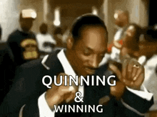 snoop dogg is wearing a suit and tie and is quinning and winning .