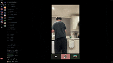 a computer screen shows a man standing in a kitchen with a black shirt that says jm on the back