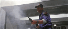 a man holding a gun in a dark room with smoke coming out of the window