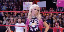 a woman is standing in a wrestling ring holding a sign that says `` i 'm a miss bliss ''