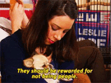 a woman holding a small animal with the words " they should be rewarded for not being people "