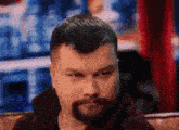 a man with a beard is sitting on a couch and looking at the camera