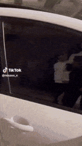 a tiktok video of a white car with a black window