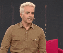 a man wearing a brown shirt has a microphone on his ear